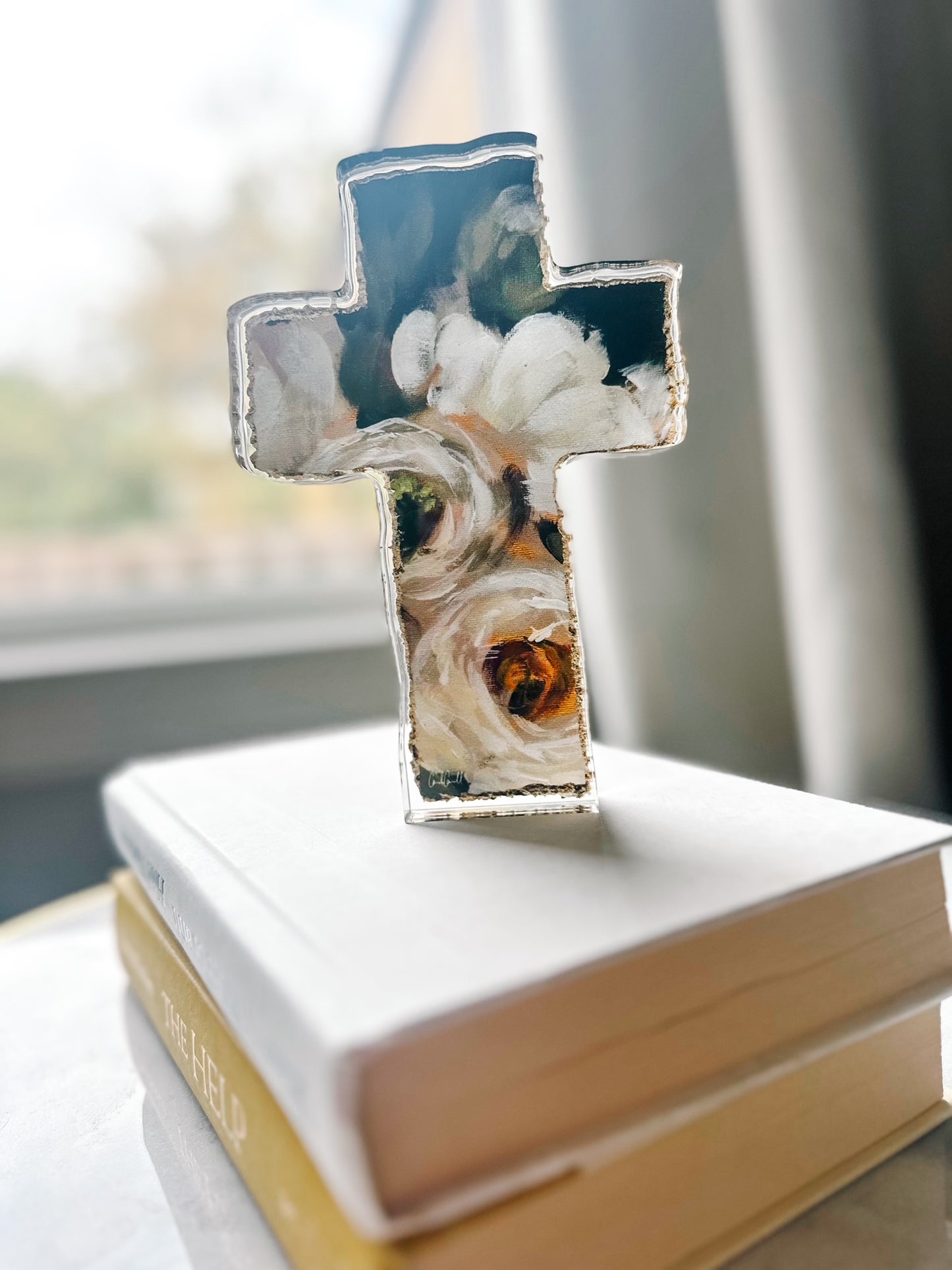 black and white floral art acrylic cross standing on books