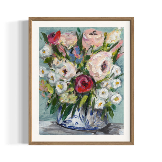 art print of floral bouquet with pink white, red, and blue flowers on aqua blue background framed in wood frame on white wall