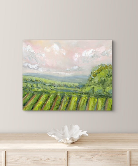 Painting of a vineyard on a wall above a wooden cabinet with a decorative bowl.