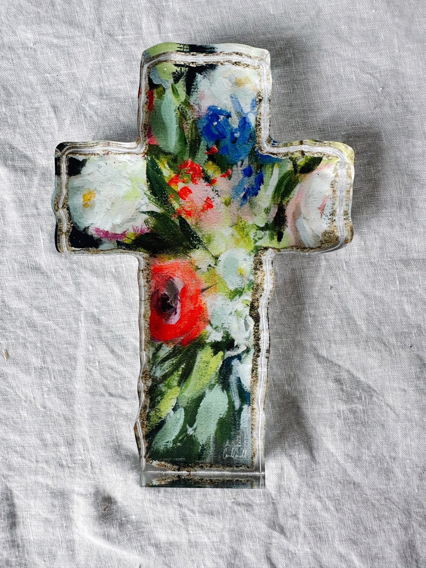 floral acrylic cross laying on white background