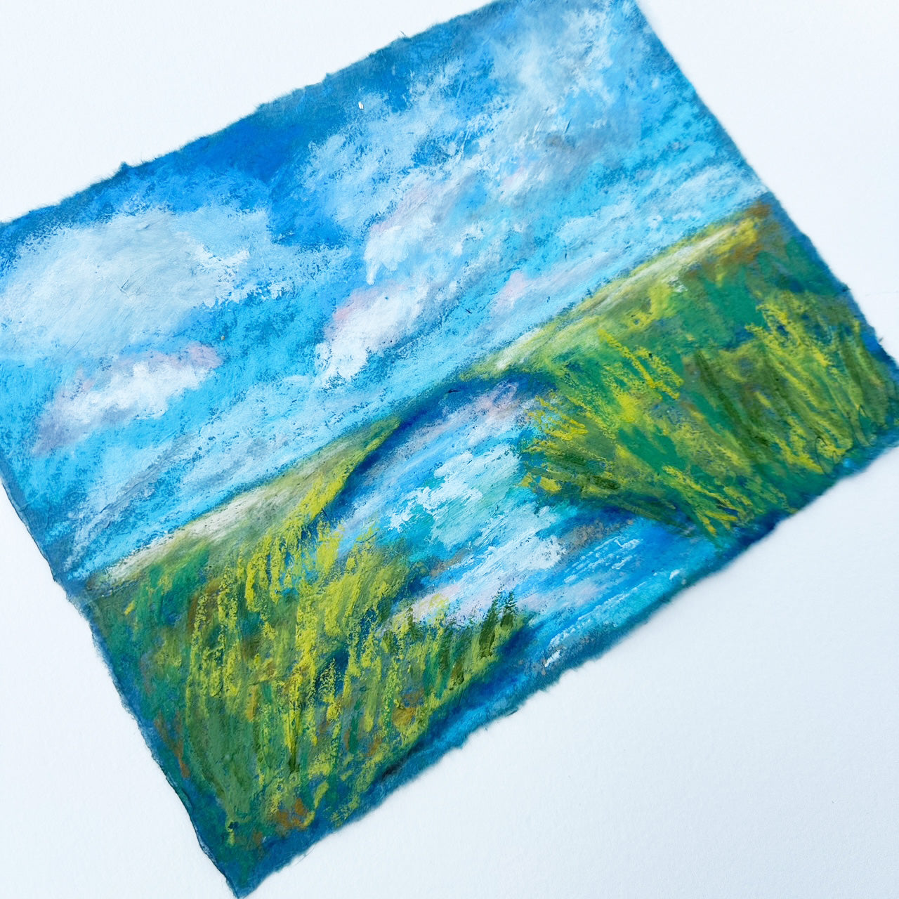 Textile art piece with blue sky and green landscape